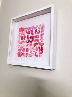 a white frame with some pink and red letters on the wall in front of it