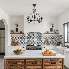 a kitchen with an island, sink and stove in the center surrounded by white cabinets