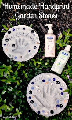 two homemade handprinted garden stones sitting in the grass next to a bottle of lotion