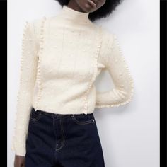 Size: S Color: Light Ecru Ref. 4331/136 High Collar Long Sleeve Sweater. Pompons And Lace Ruffle Detail. Main Fabric: 55% Acrylic. 4% Elastane. 28% Polyester. 13% Polyamide Lace: 100% Cotton Chic Sweater With Ruffles For Layering, Chic Ruffled Sweater For Layering, Cream Fitted Sweater With Ruffles, Fitted Cream Sweater With Ruffles, Chic Fitted Sweater With Ruffles, White Ruffled Sweater For Spring, Chic Cream Pointelle Knit Sweater, Casual Cream Sweater With Ruffles, Chic Knit Sweater With Ruffles