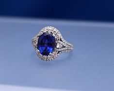 an oval shaped blue and white diamond ring on a light blue surface with diamonds surrounding it