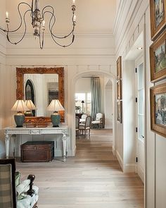 the hallway is decorated with antique furniture and mirrors, along with two lamps on either side of the console table