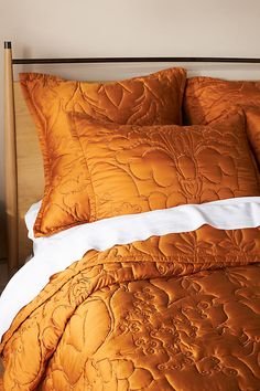 an orange comforter and pillows on a bed