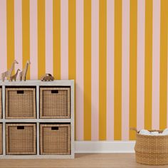 a room with yellow and pink striped wallpaper, wicker baskets on the floor