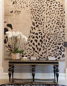 a black and white table with flowers on it in front of a leopard print wall