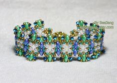 a close up of a bracelet on a white surface with blue and green beading