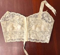 This camisole is from the time that the camisole was becoming a bra.  It has a label of 2 words.  I'm not sure of the first word, it resembled Scott's; the second word is Ideal.  It shows Chicago.  I've not found any mention of this name. This sweet garment is made of silk and filet lace.  The silk cups have some deteriorated holes.  One strap is missing and the other is frayed.  These could easily be replaced.  The label is attached at the bottom of the camisole.  The closure is hook and eyes. Vintage Corset With Boned Bodice, Vintage Sleeveless Top With Built-in Bra, Vintage Camisole With Built-in Bra For Summer, Vintage Summer Camisole With Built-in Bra, Vintage Cami Top For Daywear, Fitted Vintage Camisole, Vintage Lace Trim Camisole Top, Vintage Fitted Sleeveless Camisole, White Vintage Cami Top