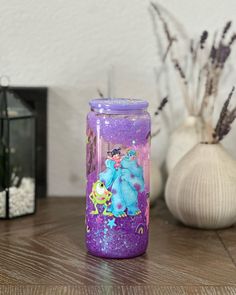 there is a purple glass with an image of the princess and prince on it next to some plants