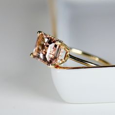 Beautiful emerald cut peachy pink color morganite ring, diamond hidden halo ring. DETAILS ABOUT THE RING!* 9x7mm emerald cut morganite is peach pink color.* Ring band is 1.3mm 14k solid yellow gold* Emerald cut 4 prong setting is 14k solid yellow gold* Set 20 white diamonds in the hidden halo, total 0.05 ct. weight. *** All our raw materials are sourced from US-based companies for the quality and safety of our handmade products.*** this ring is handcrafted for you in our local studio in Redlands Blush Morganite Rings With Prong Setting, Blush Morganite Ring With Prong Setting, Elegant Morganite Rings With Baguette Cut, Morganite Ring With Prong Setting For Proposal, Morganite Rings With Prong Setting For Proposal, Elegant Morganite Radiant Cut Rings, Emerald-cut Topaz Ring In Rose Gold, Morganite Radiant Cut Jewelry For Anniversary, Radiant Cut Morganite Rings For Anniversary