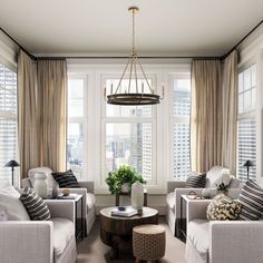 a living room with couches, chairs and a table in front of two windows