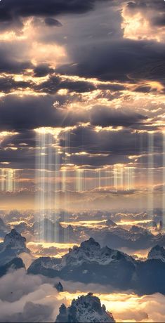 the sky is filled with clouds and light beams that are shining in the distance over mountains