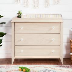 a baby crib next to a potted plant in a room with white walls