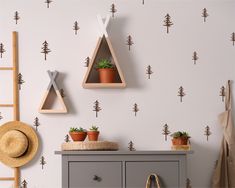 the wall is decorated with small trees and plants on shelves, along with a hat rack