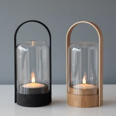 two wooden and glass candle holders on a table