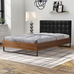 a modern bedroom with white walls and wood flooring, including a black headboard