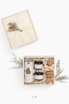 an open gift box containing honey, cookies and soaps on a white background with greenery