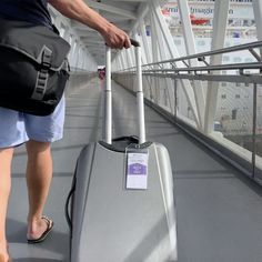 a person pulling a suitcase across a bridge with their feet on the railing and luggage in hand