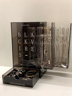 three different types of jewelry are displayed in glass cases on a white surface, one is black and the other is silver