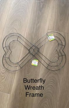 the butterfly wire frame is on top of wood flooring and has two tags attached to it