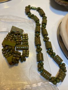 two necklaces sitting on top of a table next to a plate with silverware