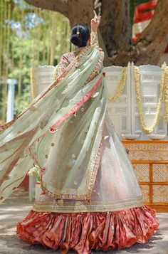 A tulle peshwas, featuring zardoze and resham embroidery, is paired with a salmon pink brocade lehnga and choli. Paired with a mint green organza dupatta accentuated with gota details and tassels. Pista Green Lehenga With Resham Embroidery In Organza, Pista Green Organza Lehenga With Resham Embroidery, Pista Green Organza Choli With Cutdana, Pista Green Organza Choli With Sheer Dupatta, Pista Green Organza Bollywood Traditional Wear, Bollywood Style Pista Green Organza Traditional Wear, Pista Green Bollywood Organza Traditional Wear, Semi-stitched Organza Anarkali Set For Traditional Ceremonies, Pista Green Dupatta With Zari Work For Reception