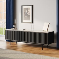 a black and white sideboard sitting on top of a wooden floor next to a window