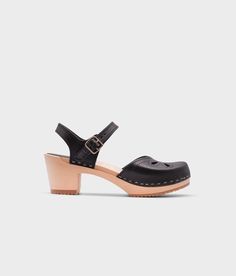 high-heeled clog sandal in black vegetable tanned leather with a blossom cut-out over the toe stapled on a light wooden base Cork Sandals, Wooden Clogs, Clog Sandals, Stylish Sandals, About Fashion, Boot Shop, Black Sandals, Natural Materials, Copenhagen