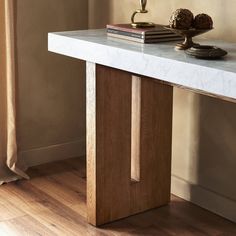 a white marble table with two books on it and a candle in the corner next to it