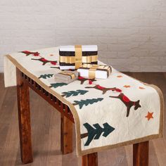 a table covered with christmas decorations and wrapped presents on it's top, sitting on a hardwood floor