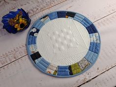 a blue and white plate sitting on top of a wooden table next to a vase