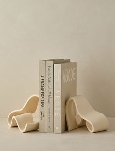 two bookends sitting next to each other in front of a white wall with books on it