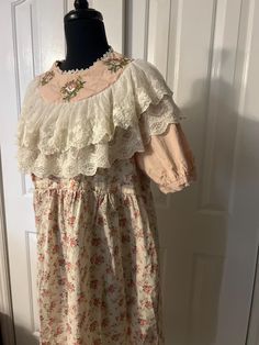 This is a gorgeous vintage Victorian/English farm style dress. Reminds me of Little House on the Prairie!  This dress is quite small and fit on a small size 1-3 mannequin Armpit to armpit 21" Collar 9" across  Top of shoulder to sleeve end 13" Sleeve diameter 12"  Length approx 44" It is in perfect condition Cottagecore Victorian Dress For Daywear, Cottagecore Embroidered Dress For Garden Party, Cottagecore Dresses With Lace Trim, Cotton Victorian Dress With Lace Trim In Cottagecore Style, Cottagecore Vintage Cotton Dress With Ruffles, Cottagecore Embroidered Short Sleeve Dress, Cottagecore Vintage Dress With Ruffles, Cottagecore Cream Dress With Floral Embroidery, Cream Victorian Dress In Cottagecore Style For Spring