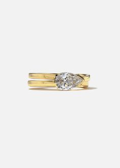 a yellow gold ring with a pear shaped diamond on the top and two thin bands around it