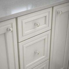 a white kitchen with marble counter tops and drawers on each side is pictured in this image