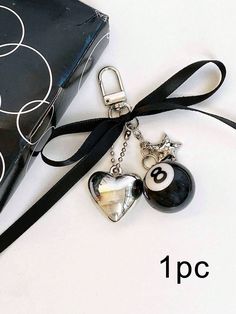 a black and white bag with two charms attached to it, next to a box