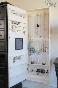 an open storage case with jewelry hanging on the door and necklaces attached to it