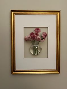 a vase filled with pink flowers sitting on top of a white table next to a wall