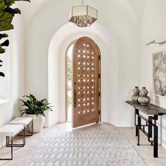 the entryway is decorated in white and features an arched wooden door with glass panels