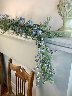 a wooden chair sitting next to a white fireplace with blue flowers on the mantel