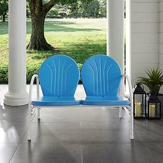 two blue chairs sitting on top of a white porch next to a large green tree