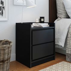 a night stand with two drawers and a lamp on it in a bedroom next to a bed