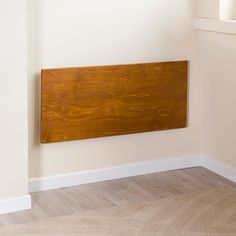 a wooden sign mounted to the side of a wall in an empty room with hard wood flooring