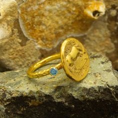 Greek  Horse Coin Signet Ring | 24K Gold Plated 925 Sterling Silver | Stackable CZ Stone Ring | Mythological Jewelry | Roman Ring Handcrafted hammered full round ring band size measures 2mm in width and 24k gold plated bronze coin 17x17 mm.Metal : 925 Sterling SilverBand Width : 2 mmGem Stone : Blue Diamond Cut Cubic ZirconiaGem Color : Green,Navy Blue,Purple,Blue,White,Red(The color you want is made for free).Gem Size : 3 mmCoin : Reproduction Bronze CoinCoin Size : 17x17 mmRing Weight : 6.45 g Gold Open Ring Topaz Ring For Gift, Handmade Gold Topaz Promise Ring, Gold Topaz Birthstone Ring In Sterling Silver, Handmade Yellow Gold Topaz Ring Gift, Handmade Gold Topaz Ring, 22k Gold Byzantine Style Rings As Gift, Handmade Gold Topaz Ring In Sterling Silver, Handmade Gold Topaz Ring For Gift, Greek Horse