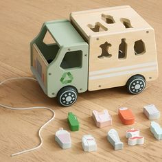 a wooden toy truck with different shapes and sizes on the floor next to other toys