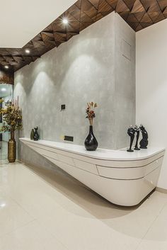 a long white counter with vases and flowers on it in front of a wall