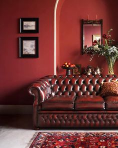 a living room with red walls, leather couches and rugs on the floor