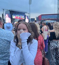 a woman covers her face as she stands in front of an audience at a concert