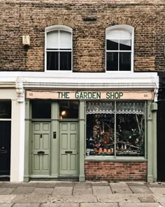 the garden shop is located in an old brick building with white trim and green doors