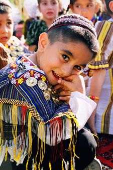 a group of young children standing next to each other in front of some people wearing colorful clothing