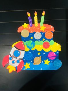 a birthday cake that is shaped like an outer space rocket ship with candles on it